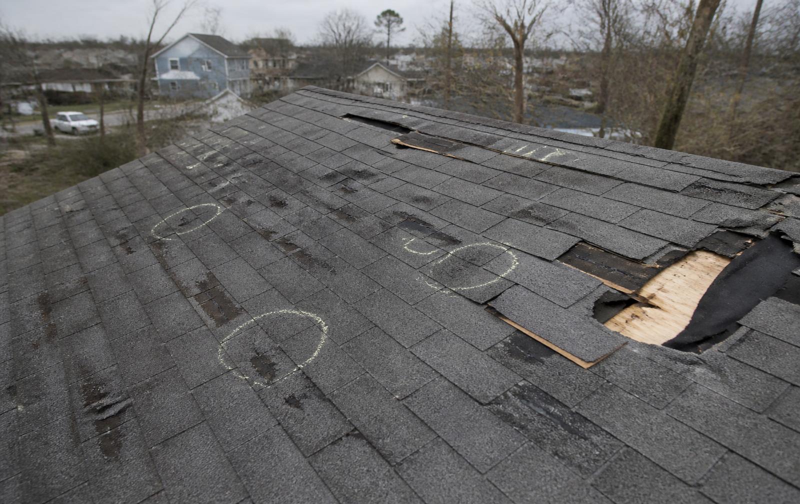 Hail damaged roof shingles marked with chalk circles